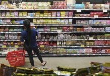 Consumidor selecciona jitomates y papas en un mercado popular mexicano mientras consulta precios de la canasta basica