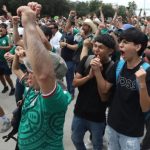 Aficionados celebran un gol en la tribuna mostrando los beneficios de la salud mental futbol al unirse en comunidad